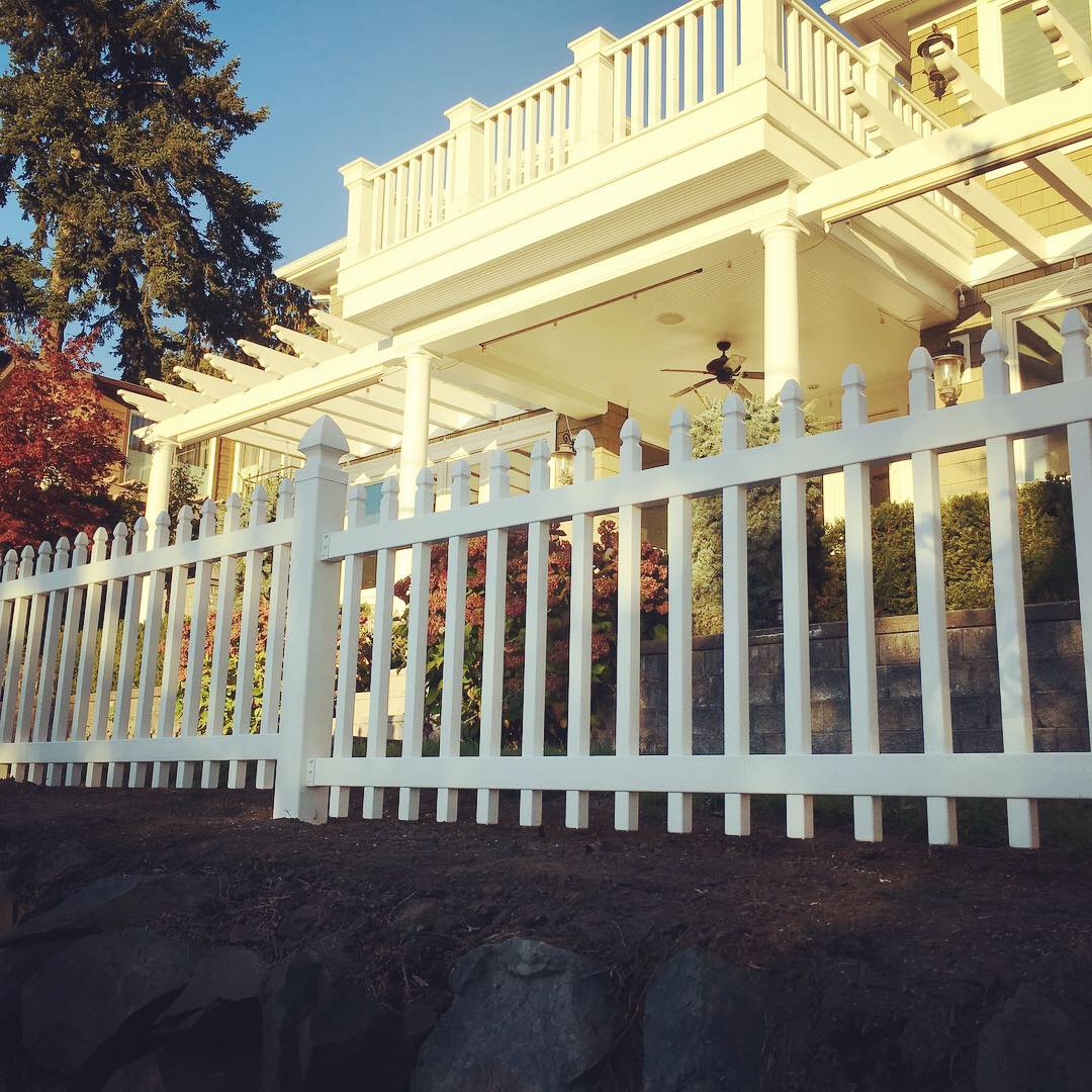 A white vinyl fence and matching deck railing among trees