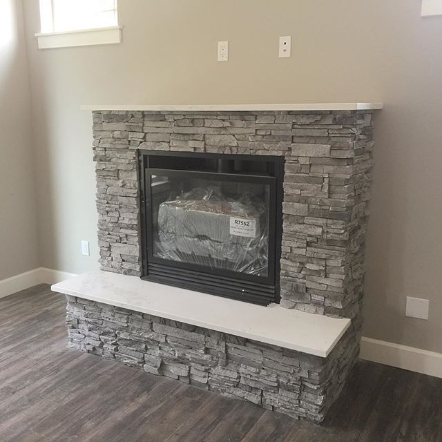 A great room with a stacked-stone fireplace and wood-look floors
