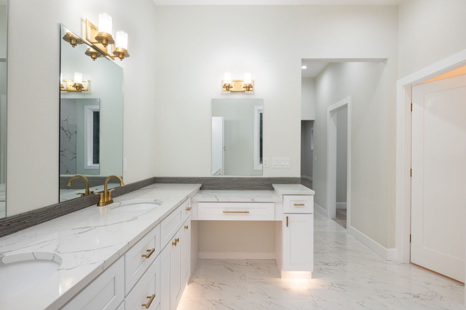 A refined bathroom with quartz counters, a large mirror and warm fixtures